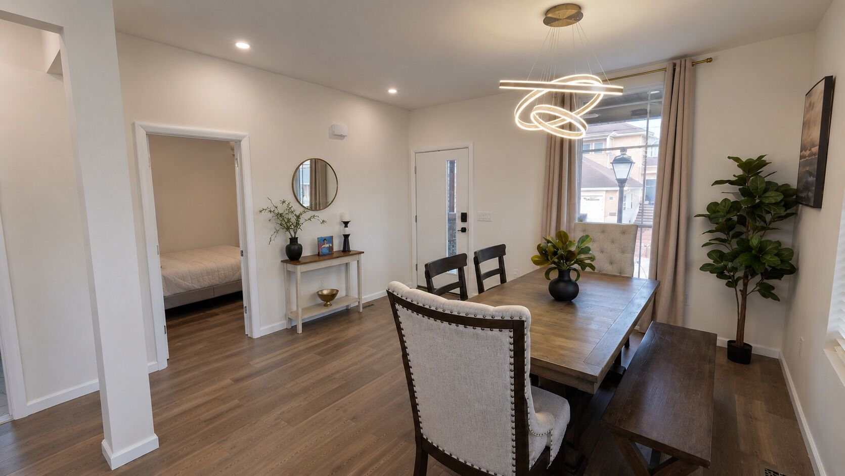Uma sala de jantar com mesa de madeira, cadeiras e uma luminária pendente moderna.