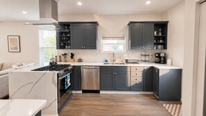 Une cuisine moderne avec des meubles de couleur sombre, un lave-vaisselle en acier inoxydable et une cuisinière à gaz.