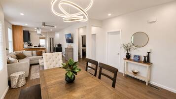Uma sala de estar moderna com uma mesa de jantar, sofás e uma televisão.