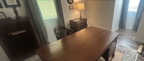 A dining area with a wooden table, chairs, a lamp, and a clock on the wall.