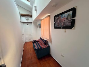 A narrow room with a bed, a door, and a painting on the wall. - Hotel Choqechaka  (Cusco)