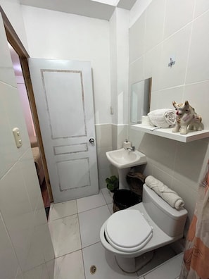 A compact bathroom with a toilet, sink, and a small shelf with a decorative item. - Hotel Choqechaka  (Cusco)