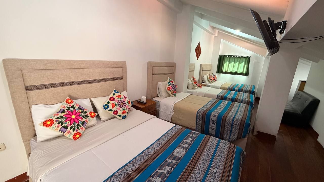 A hotel room with two beds, each with patterned bedding and decorative pillows.