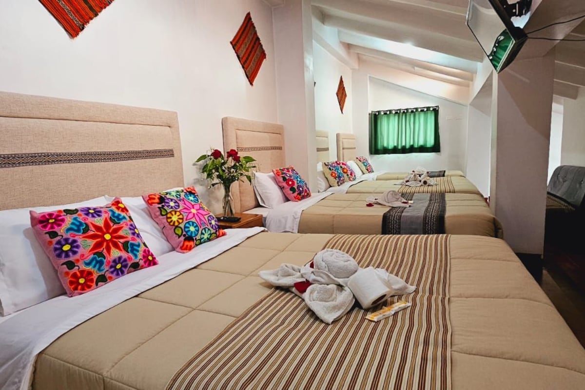 A hotel room with two beds, a desk, a chair, and a window with curtains.