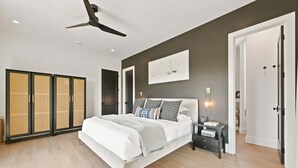 Un dormitorio moderno con una cama grande, un ventilador de techo y un armario con puertas correderas.