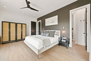 Ein modernes Schlafzimmer mit einem großen Bett, einem Deckenventilator und einem Schrank mit Schiebetüren.