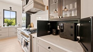 Una cocina moderna con electrodomésticos de acero inoxidable, horno empotrado y un amplio ventanal con vistas al follaje.