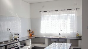 A modern kitchen with a central island, a built-in oven, and a window with curtains.