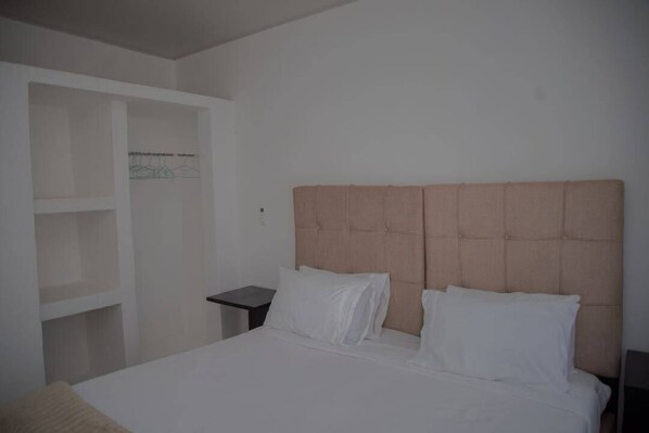 A bedroom with a bed, a nightstand, and built-in shelving.