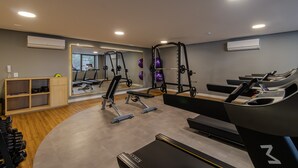 A gym with treadmills, weight machines, and a mirrored wall. - Studio com Piscina perto do metrô Vila Mariana (São Paulo)