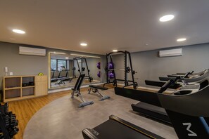 Ein Fitnessstudio mit Laufbändern, Krafttrainingsgeräten und einer Spiegelwand.