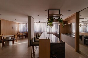 Una cuina moderna amb una illa llarga, una zona de menjador amb taula i cadires, i un taulell de cuina amb un rentaplat.