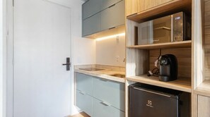 A compact kitchen with a microwave, coffee machine, and a refrigerator. - Studio with Pool near the Subway | Vila Mariana (São Paulo)