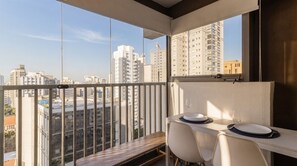 Ein Balkon mit Esstisch und Stühlen, mit Blick auf eine Stadtlandschaft mit Hochhäusern.
