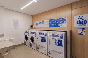 Una sala amb bugaderia, diverses rentadores, una paret de fusta amb cartells informatius i un terra de rajola.