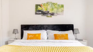A bed with two pillows, a headboard, bedside tables, and a wall-mounted artwork.