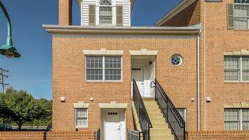 A two-story brick building with a central entrance, a staircase, and a small dormer window.