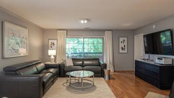 A modern living room with a leather sofa, a glass coffee table, and a flat-screen TV.