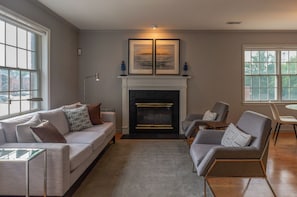 A modern living room with a fireplace, a sofa set, and a dining area. - Terrific Townhome with 2-Bedroom Ensuites in Arlington (Arlington)