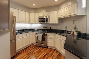 A modern kitchen with white cabinetry, stainless steel appliances, and a wooden floor. - Terrific Townhome with 2-Bedroom Ensuites in Arlington (Arlington)