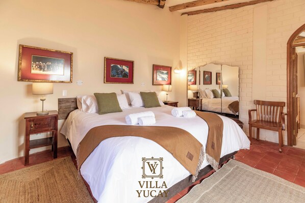 A hotel room with a large bed, two bedside tables, a wooden bench, and a mirror on the wall.