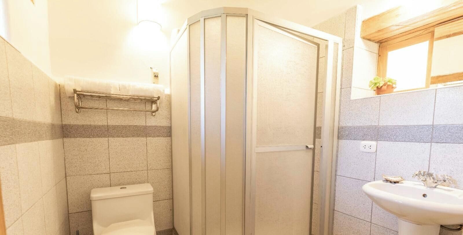 Un baño con inodoro, cabina de ducha y lavamanos.