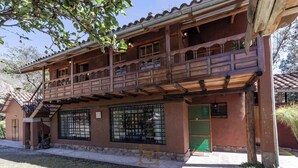 Un edificio de dos pisos con un balcón, una entrada protegida por una reja y una pequeña zona de porche.