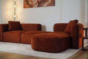 Ein Ecksofa in einem Wohnzimmer mit einem hellen Teppich und einer Stehlampe mit mehreren Lampenköpfen.