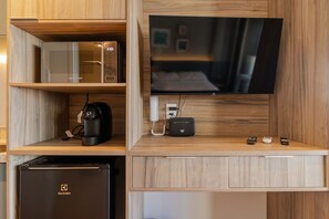A compact hotel room with a microwave, coffee maker, and a refrigerator on the left, and a flat-screen TV on the right. - Studio com Piscina Perto do Metr Vila Mariana (São Paulo)