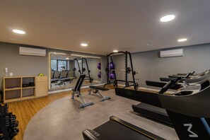 Ein moderner Fitnessraum mit Laufbändern, Krafttrainingsgeräten und einer Spiegelwand.