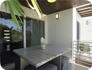 Ein Essbereich mit Tisch und Stühlen, ein Fenster mit Vorhängen und ein Balkon mit Geländer.