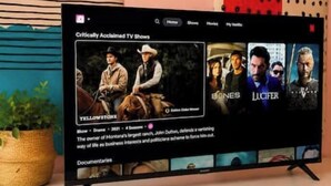 En platt-TV står på ett vitt skåp och visar användargränssnittet för en streamingtjänst, och på skärmen visas hyllade tv-serier.