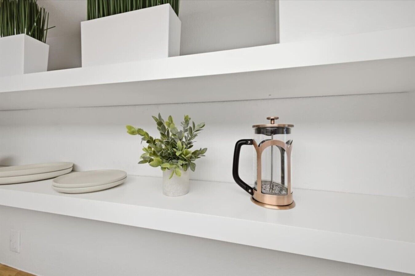 A white shelf with a coffee maker and a potted plant.