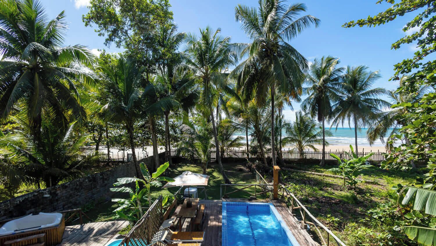 A pool area with a wooden deck, lounge chairs, and a hot tub.