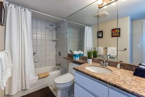A bathroom with a shower, toilet, sink, and a large mirror. - Bright 4BR, 2 Condos for 12 at Maalaea Kai! (Wailuku)