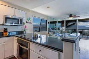 A modern kitchen with a large island, a dining area with a view, and a ceiling fan. - Maalaea, Maalaea Kai, Spacious 4 BR, Beachfront, Sleeps 12 (Wailuku)
