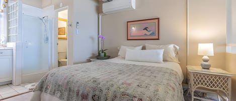 A bedroom with a bed, bedside table, lamp, and a painting on the wall.