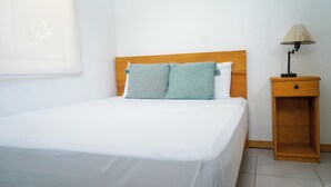 A single bed with a wooden headboard, a bedside table with a lamp, and a window with blinds. - 4-Bedroom Private Beach House with AC and access to the beach at 3-min walk (La Libertad)
