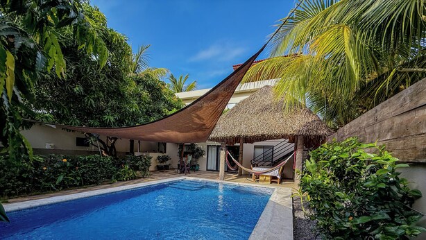 A swimming pool with a thatched-roof structure and a hammock. - 4-Bedroom Private Beach House with AC and access to the beach at 3-min walk (La Libertad)