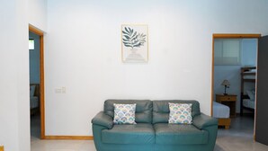 A teal leather sofa with patterned cushions in a room with white walls and a framed artwork above it. - 4-Bedroom Private Beach House with AC and access to the beach at 3-min walk (La Libertad)