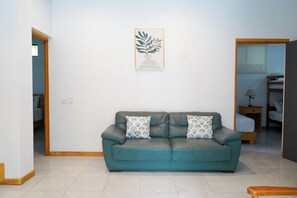 A teal leather sofa with patterned cushions in a room with white walls and a framed artwork above it. - 4-Bedroom Private Beach House with AC and access to the beach at 3-min walk (La Libertad)