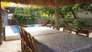 A hammock under a thatched roof, a pool, and a table with chairs. - 4-Bedroom Private Beach House with AC and access to the beach at 3-min walk (La Libertad)