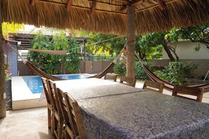 A hammock under a thatched roof, a pool, and a table with chairs. - 4-Bedroom Private Beach House with AC and access to the beach at 3-min walk (La Libertad)