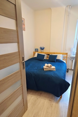 Ein Schlafzimmer mit einem Bett, einem hölzernen Kopfteil und einem Fenster mit Vorhängen.