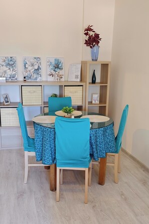 Ein Essbereich mit einem runden Tisch, vier Stühlen und einer blau-blumigen Tischdecke.