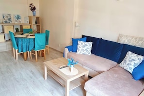 Ein Wohnzimmer mit Sofa, Couchtisch und einem Essbereich mit Stühlen und Tisch.