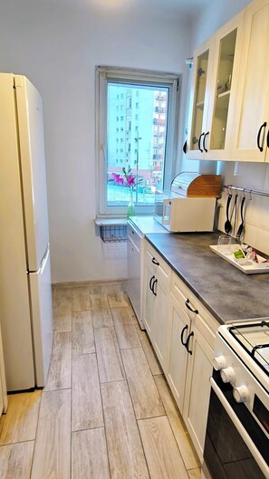 Eine kleine Küche mit Kühlschrank, Mikrowelle, Herd und Schränken.