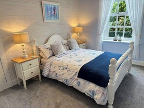 A bedroom with a bed, bedside tables, a window with curtains, a wall-mounted picture, and a carpeted floor. - Largo Bay - Harbour Hideaway (Leven)