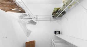 A storage area with metal shelves, a wooden basket, and a small black device on a white wall. - Comfort 2BR - Private Balcony & Beach access (Sunny Isles Beach)