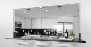A modern kitchen with a central island, stainless steel appliances, and a wine bottle on the counter. - Comfort 2BR - Private Balcony & Beach access (Sunny Isles Beach)